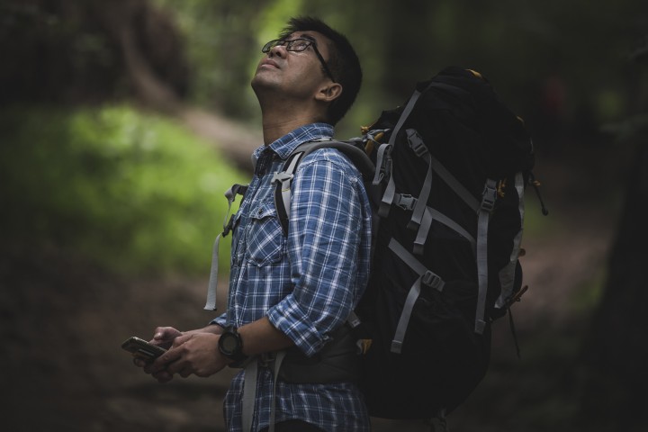 Hiker with backpack and smart phone, looking up