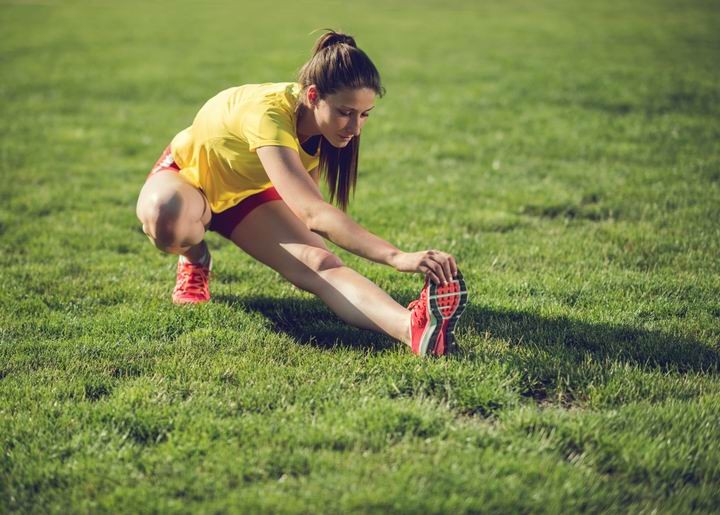 Young female athlete stretching her leg in nature.